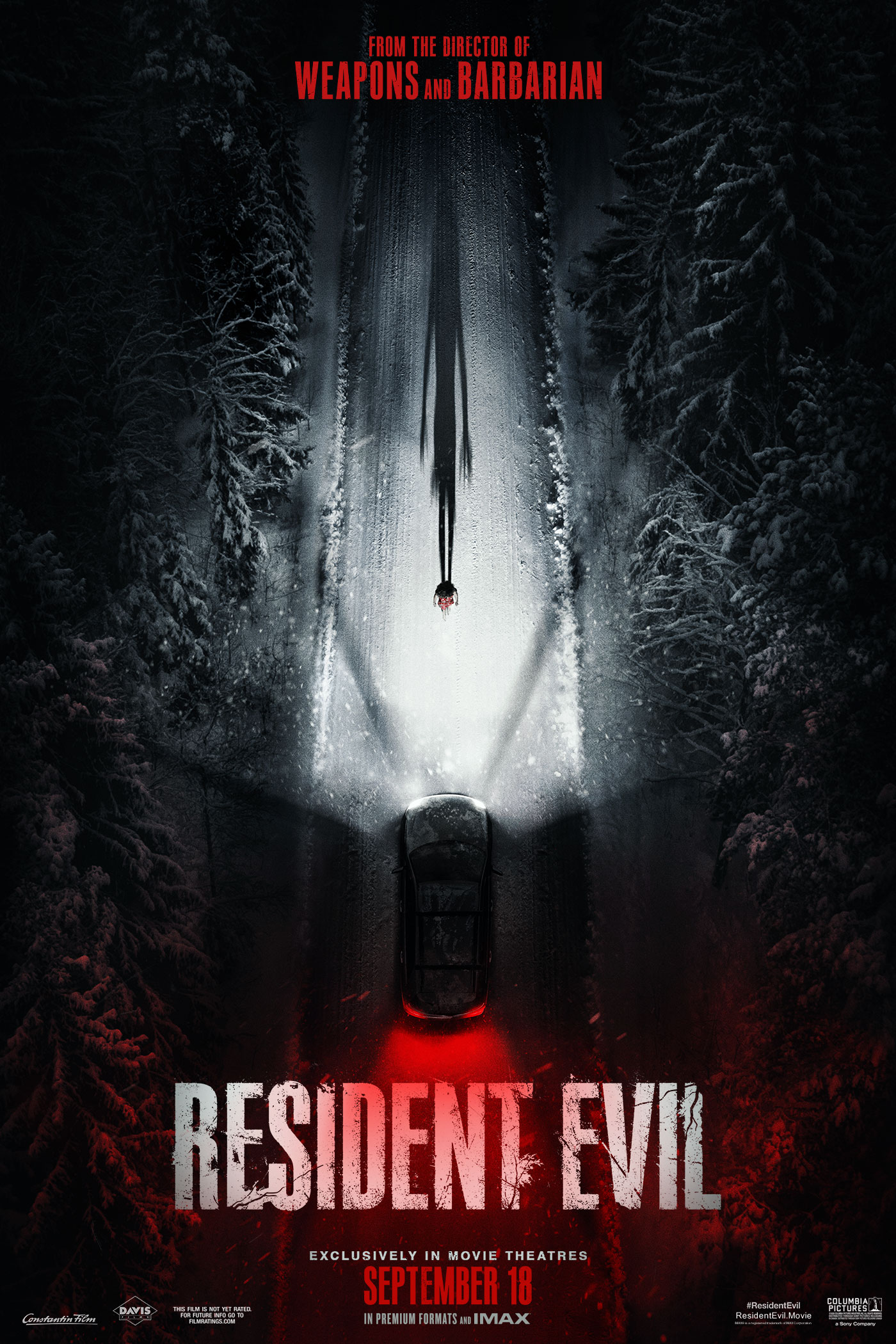 Resident Evil poster showing a car's headlights illuminating a figure and long shadow on a snowy forest road